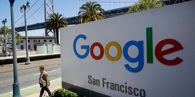 FILE - In this May 1, 2019, file photo a man walks past a Google sign outside with a span of the Bay Bridge at rear in San Francisco. A group of states are expected to announce an investigation into Google on Monday, Sept. 9, to investigate whether the tech company has become too big. (AP Photo/Jeff Chiu, File)