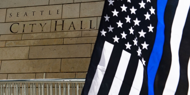 A Thin Blue Line flag waves during the Seattle Police Officers Guild's rally to stop defunding of the Seattle Police Department on Sunday, Aug. 9, 2020, at Seattle City Hall.