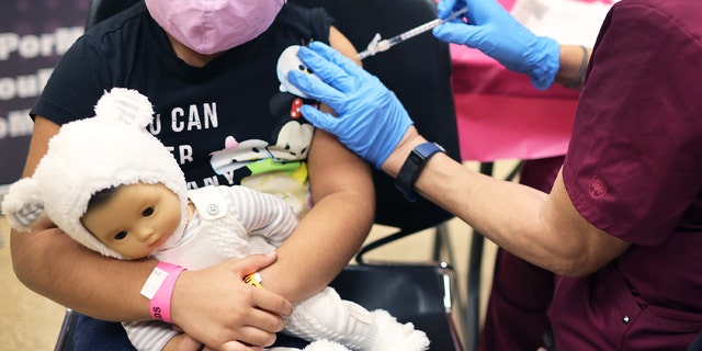 A young girl receives a COVID-19 vaccine at Arturo Velasquez Institute in Chicago, Illinois.