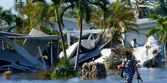 A woman walks out of her flooded neighborhood after Hurricane Ian passed by the area on Thursday, Sept. 29, 2022, in Fort Myers, Fla.