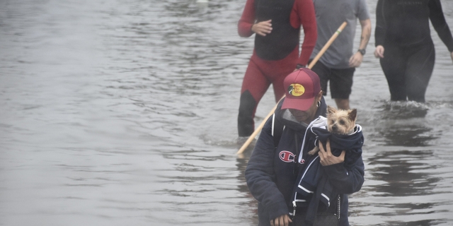A woman holds her small dog after Hurricane Ian devastated her area.