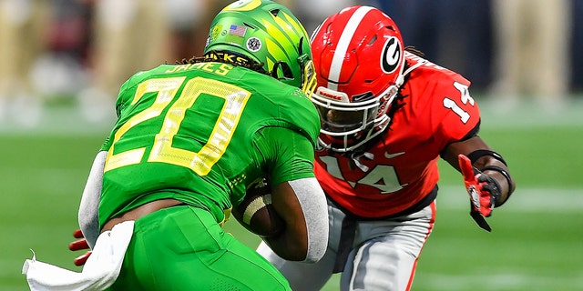Oregon running back Jordan James, #20, is tackled by Georgia defensive back David Daniel-Sisavanh, #14, during the Chick-Fil-A Kickoff Game between the Oregon Ducks and the Georgia Bulldogs on Sept. 3, 2022 at Mercedes-Benz Stadium in Atlanta.