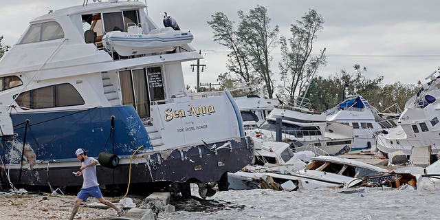 Joe Dalton, on vacation from Cleveland, Ohio, checks out beached boats at Fort Myers Wharf along the Caloosahatchee River Thursday, Sept. 29, 2022, in Fort Myers, Fla., following Hurricane Ian.