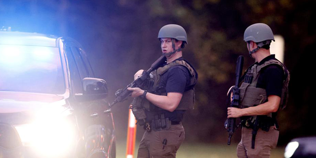 Law enforcement stand at the entrance to Neuse River Greenway Trail parking at Abington Lane following a shooting in Raleigh, N.C., Thursday, Oct. 13, 2022.
