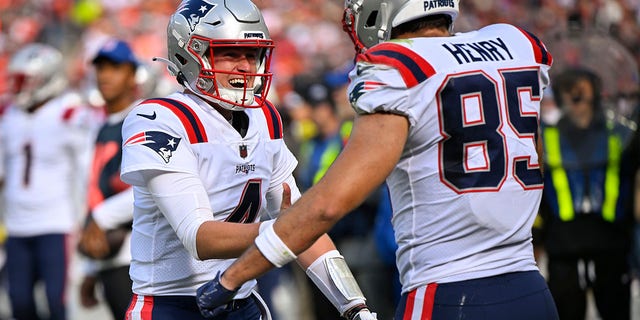 New England Patriots quarterback Bailey Zappe (4) celebrates after throwing a touchdown pass to tight end Hunter Henry (85) during the second half of an NFL football game against the Cleveland Browns, Sunday, Oct. 16, 2022, in Cleveland.