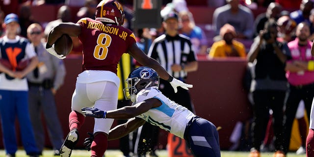 Washington Commanders running back Brian Robinson Jr., left, rushes past Tennessee Titans cornerback Roger McCreary in the first half of a game Oct. 9, 2022, in Landover, Md.