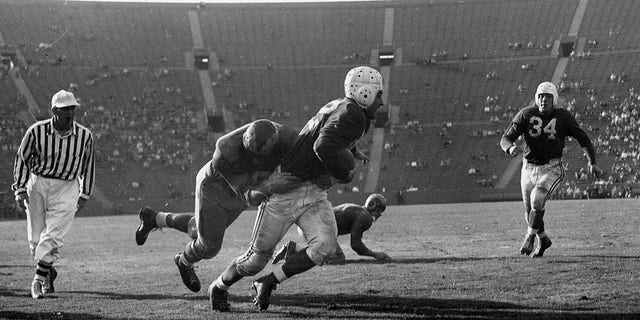 Halfback Charley Trippi of the Chicago Cardinals tries to avoid being tackled by Rams defender Pat Harder (34) in a 27-to-22 win over the Los Angeles Rams on October 31, 1948, at Los Angeles Memorial Coliseum in Los Angeles, California.