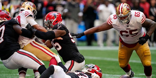 San Francisco 49ers quarterback Jimmy Garoppolo (10) is stripped of the ball by Atlanta Falcons defensive end Grady Jarrett (97) and San Francisco 49ers guard Aaron Banks (65) recovers the fumble during the first half of an NFL football game, Sunday, Oct. 16, 2022, in Atlanta.