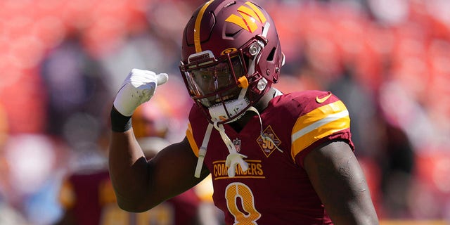 Brian Robinson #8 of the Washington Commanders warms up with running backs coach Randy Jordan before the game against the Philadelphia Eagles at FedExField on Sept. 25, 2022 in Landover, Maryland. Robinson was shot twice in the leg during an attempted robbery on Aug. 28, 2022.